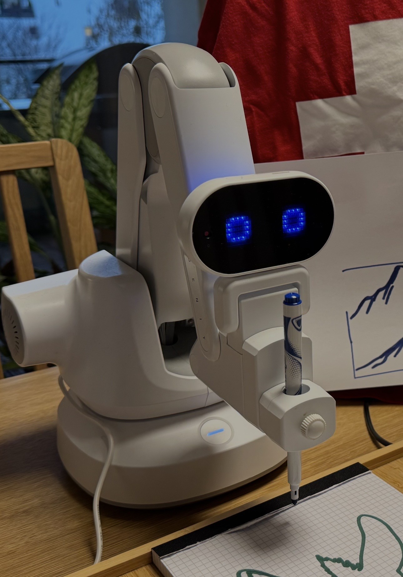 The Huenit robot arm mid-drawing, pen loaded, LED eyes lit
